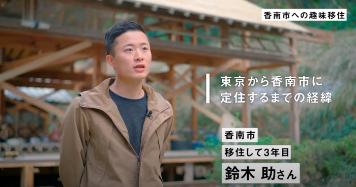 鈴木助さんが自然の中に建っている建物の前で話をしている画像