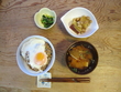 ご飯の上に焼き納豆と目玉焼きが乗せられた丼ぶり、みそ汁、小鉢を2品添えた写真