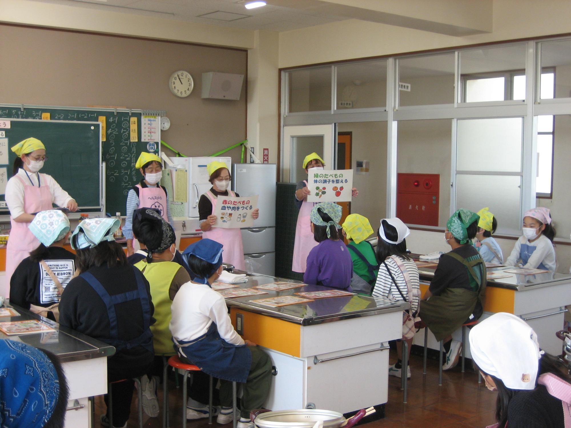 小学校5年生の朝食作り教室にてヘルスメイトが朝ごはんの働きを伝えている写真
