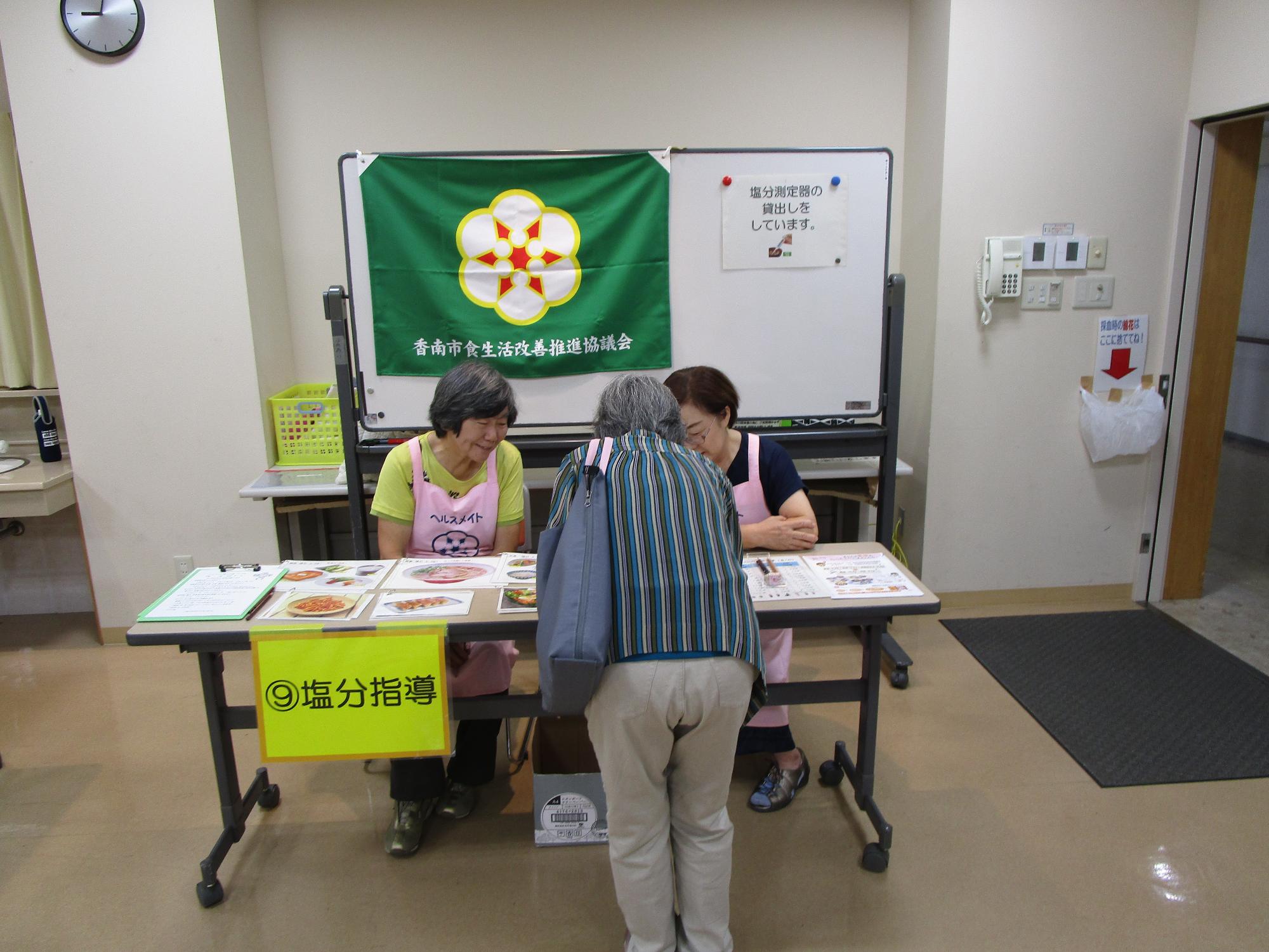 特定健診会場で実施している健診受診者に対する減塩啓発の様子の写真。パンフレットの配布やアンケート記入の様子。