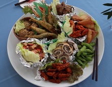 魚のフライや煮物等の海の幸とサラダや枝豆が一つの大きなお皿に盛りつけられた組み料理の写真
