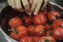 フルーツトマトを水の入った銀のボウルにつけている写真