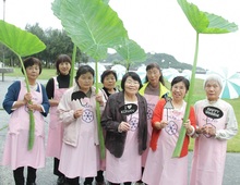 ヘルスメイトの方々女性8名が、大きな葉っぱを持っている写真。