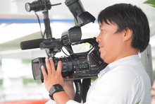 香南ケーブルテレビの男性が撮影用カメラを持って撮影している写真。