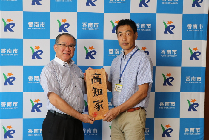 近森さんと清藤市長が高知家と書かれた大きな表札を二人で持っている写真