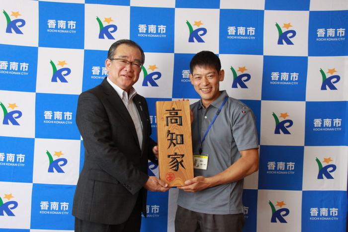 近藤さんと清藤市長が高知家と書かれた大きな表札を二人で持っている写真