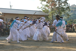 浅上王子宮で白い袴を着た男性数人が棒を持って棒踊りをしている様子の写真