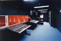 サンホールの音響調整室を映した写真。濃い青色で部屋全体が構成されており、手前に照明卓、奥には音響ミキサーが見える。