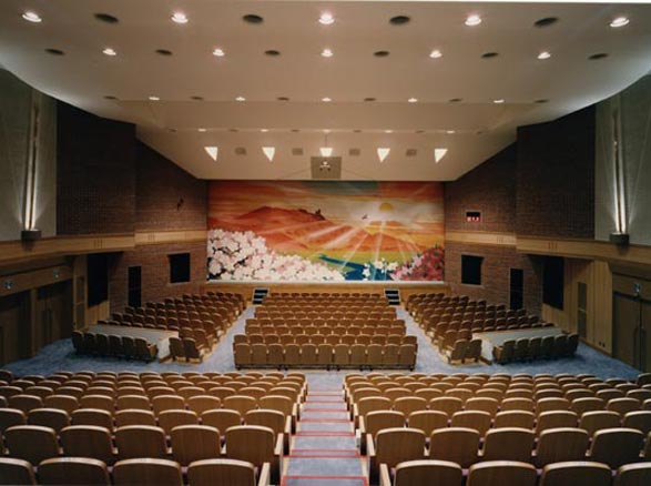 サンホールの劇場内の全体図を映した写真。舞台には夕焼けと桜をメインにした緞帳が垂れている。